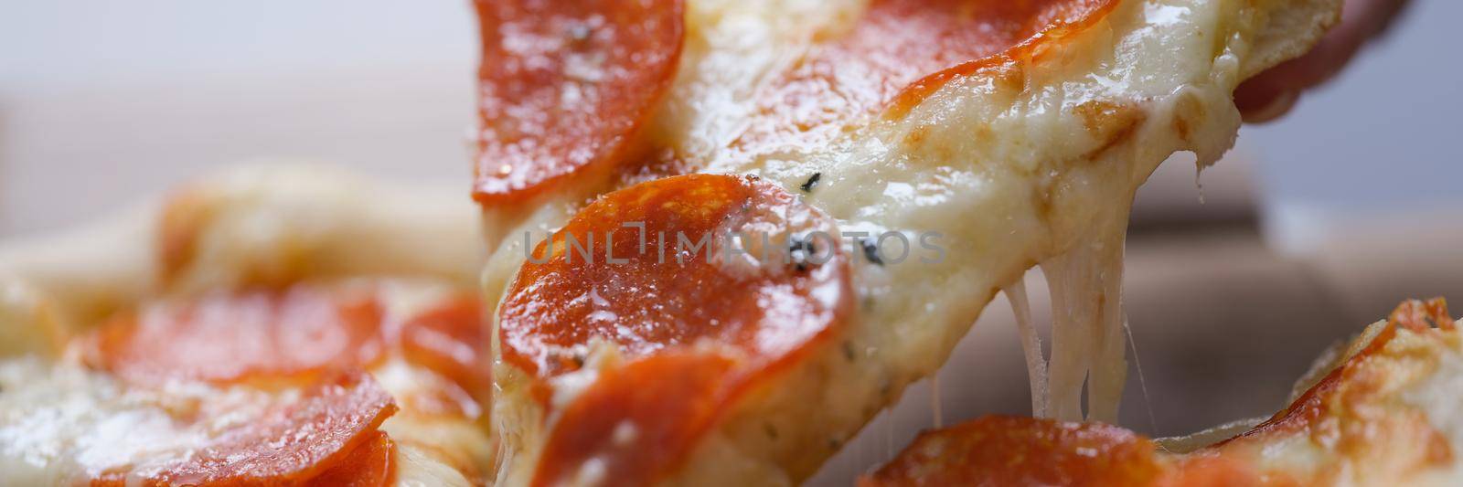 A man takes a large slice of hot neo-Politan pizza, close-up. Sausage with melted cheese on a flatbread, fast food