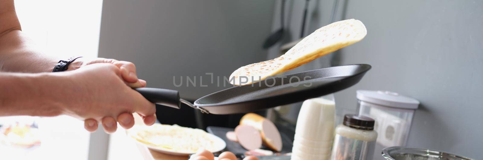 A man fries tacos in a frying pan at home in the kitchen by kuprevich