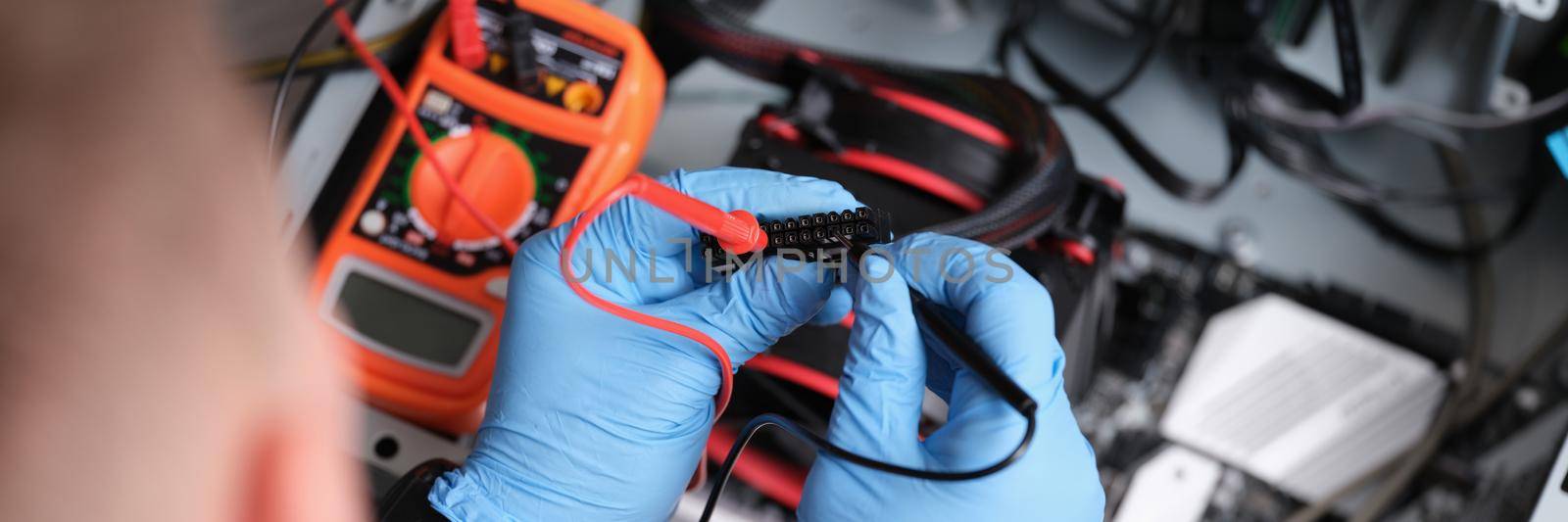 Man working with a multimeter to repair computers, close-up. Digital device, voltage measurement, upgrade pc