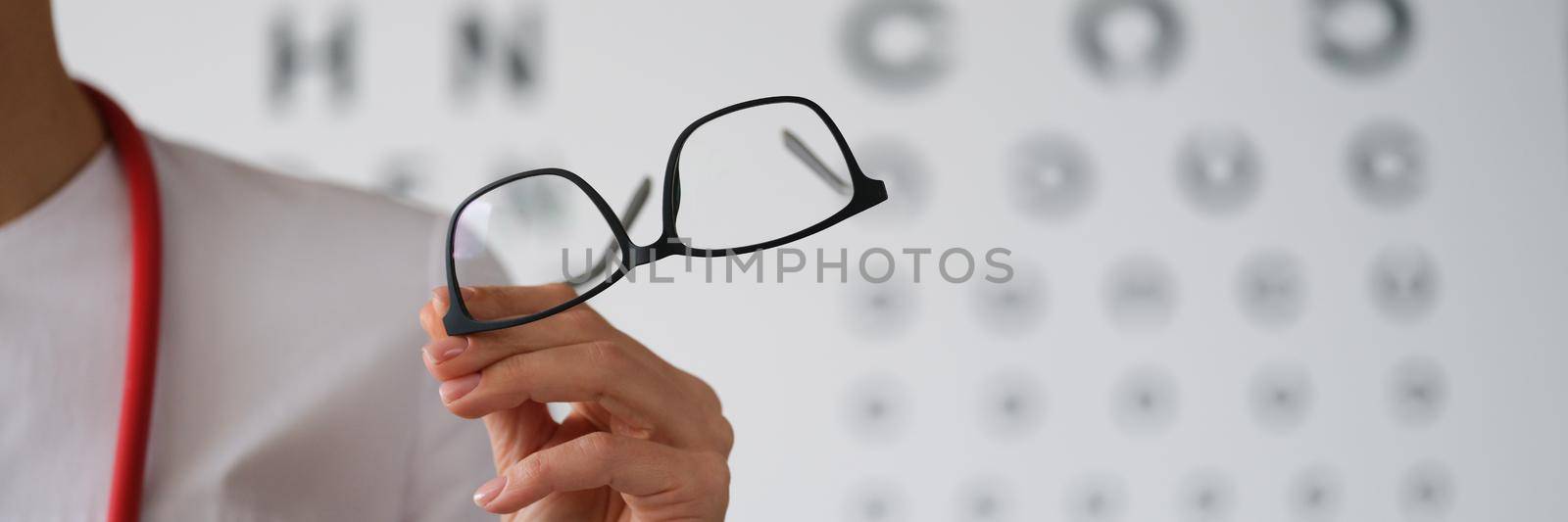 Woman doctor ophthalmologist shows glasses, close-up. Vision diagnostics, professional consultation with an eye doctor