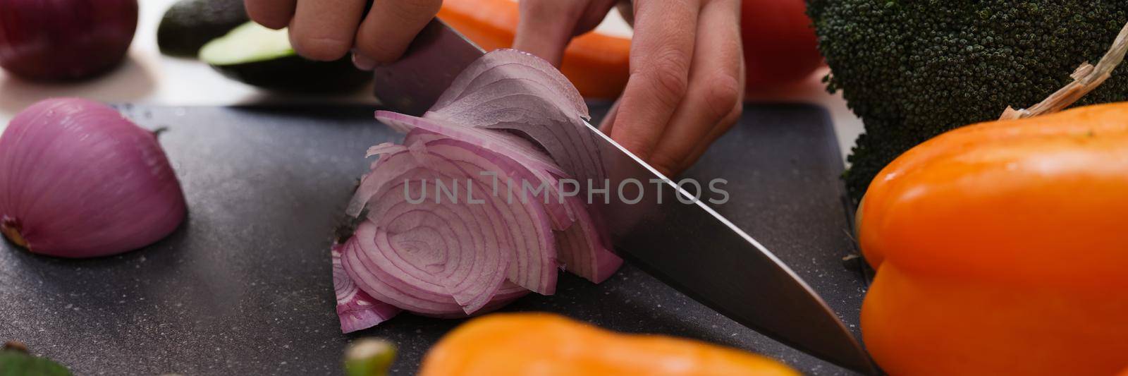 Hands cut onions on a cutting board, organic vegetables close-up. Vegan food preparation, keto diet recipe