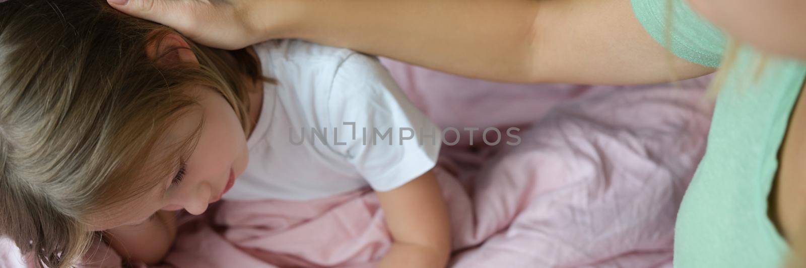 Little girl is sad on the bed, next to mom by kuprevich