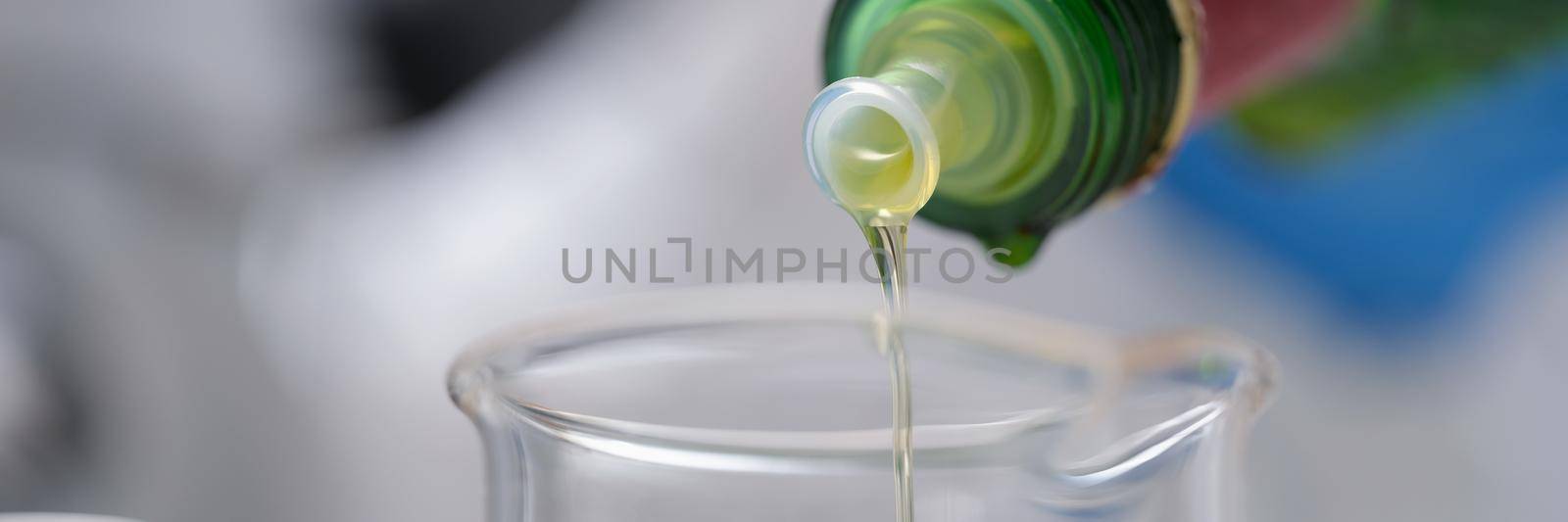 Oil from a bottle is poured into a measuring vessel, close-up. Prescription cooking dosage, portion. Quality checking