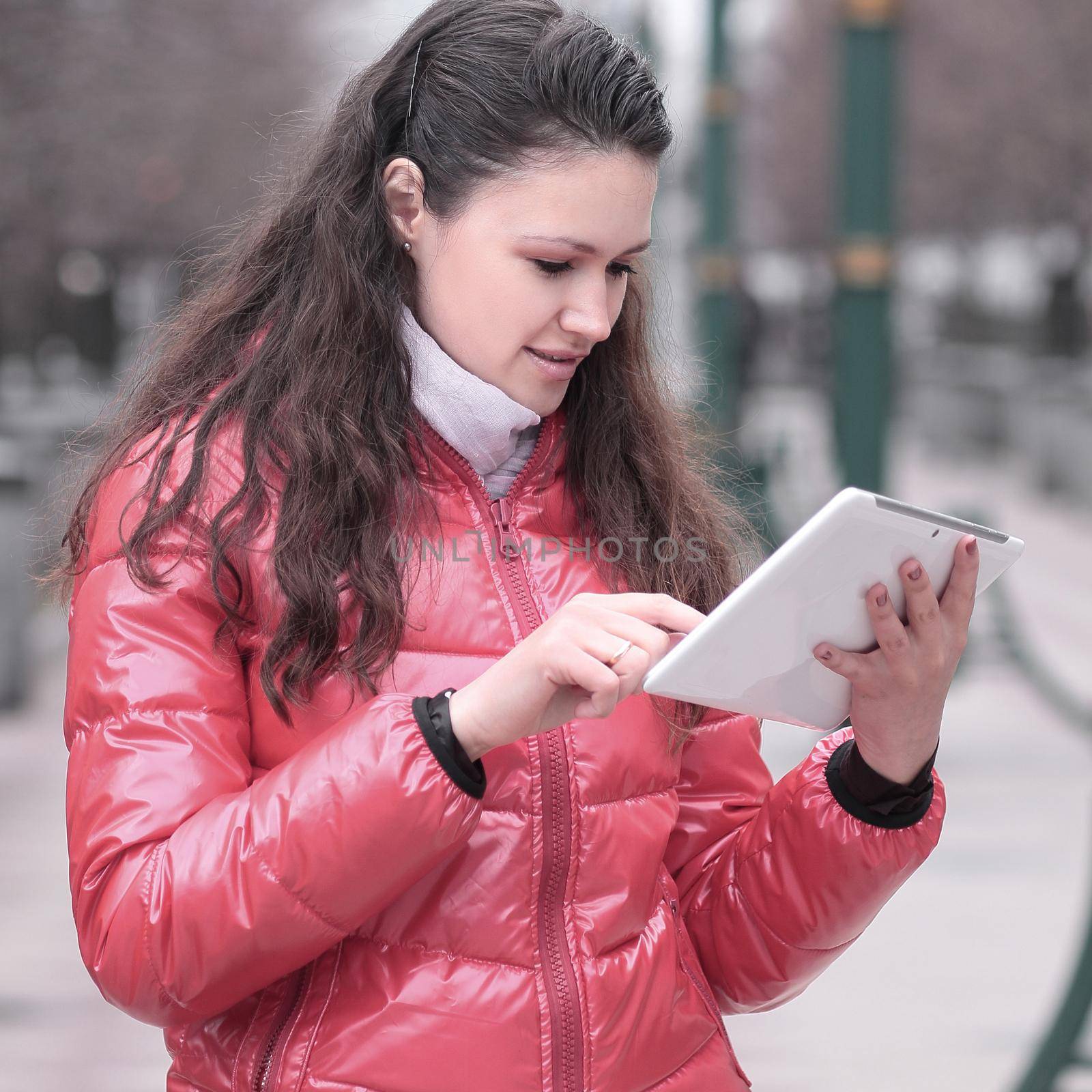 young woman with digital tablet on city background by SmartPhotoLab