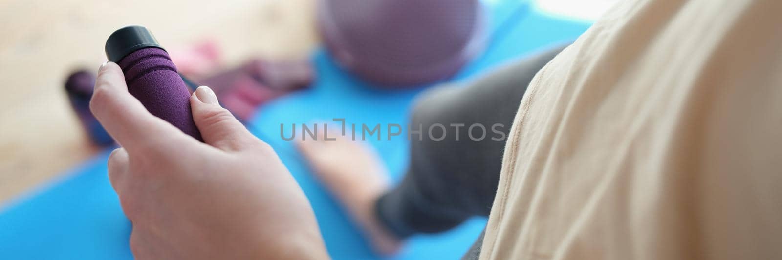 A slender woman is holding a skipping rope, close-up, blurry. Aerobics in the fitness center during lockdown