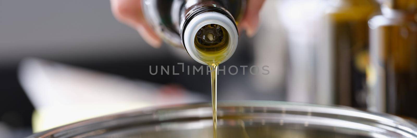 Olive oil is poured from a bottle into a saucepan, close-up. Healthy Cooking, antioxidants. Cholesterol protection