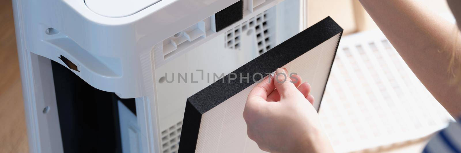 A woman is changing the filter in the air purification system, close-up. Household appliances for ionization and aromatization of the air at home