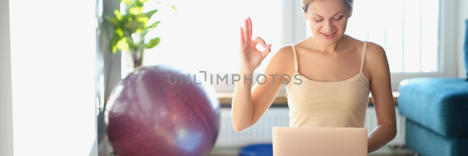 Woman with laptop getting ready for workout at home, close-up. Remote work, online meeting after charging