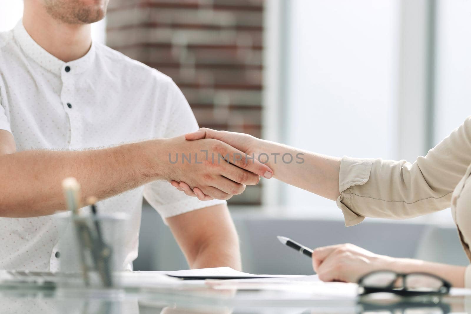 businessman and businesswoman shaking hands while sitting at the Desk. concept of cooperation
