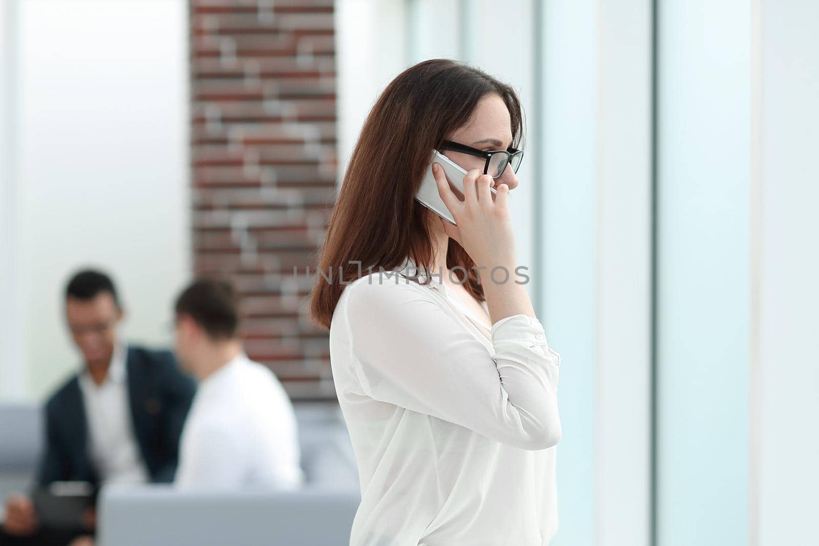 Executive business woman talking on smartphone while standing in office. business concept