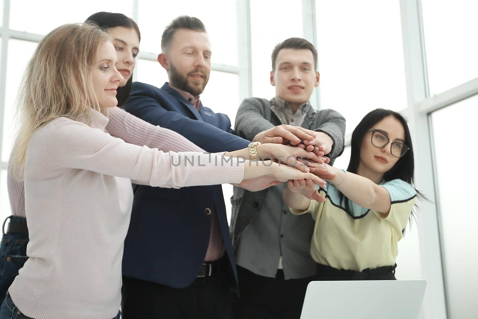 young employees joining their hands over the Desk. the concept of teamwork
