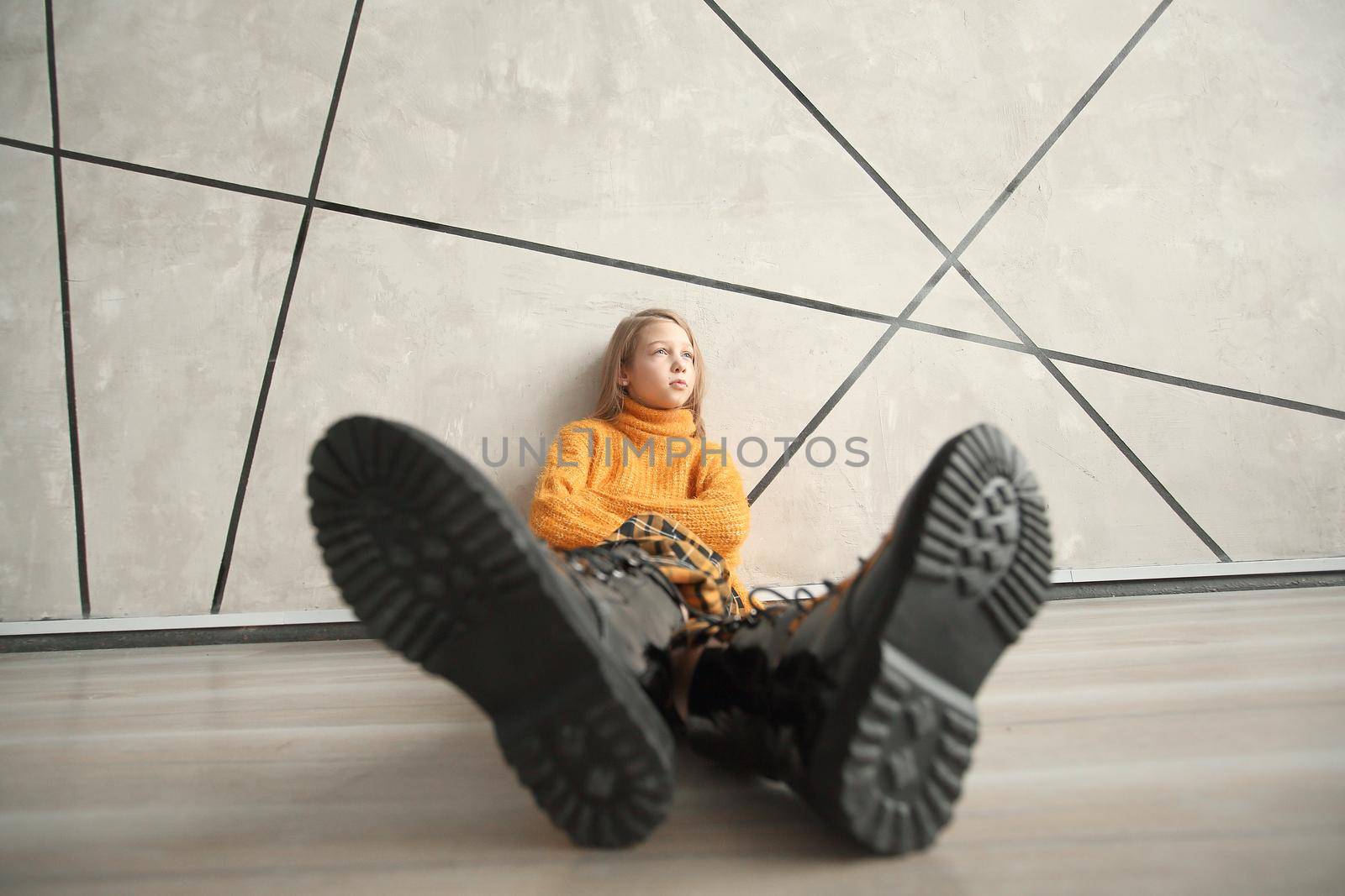 stylized photo of a girl in a yellow sweater sitting near the wall. photo with copy space
