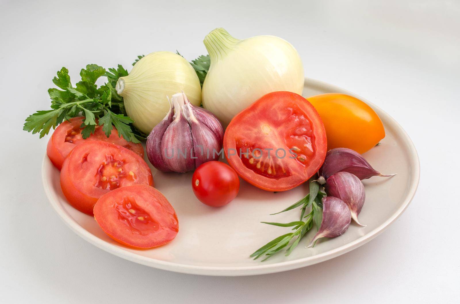 Tomatoes, garlic, onions and greens on a plate.