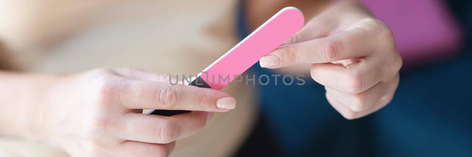 Woman holding a nail file, female hands with manicure, close-up. Correction of nails, professional hand care