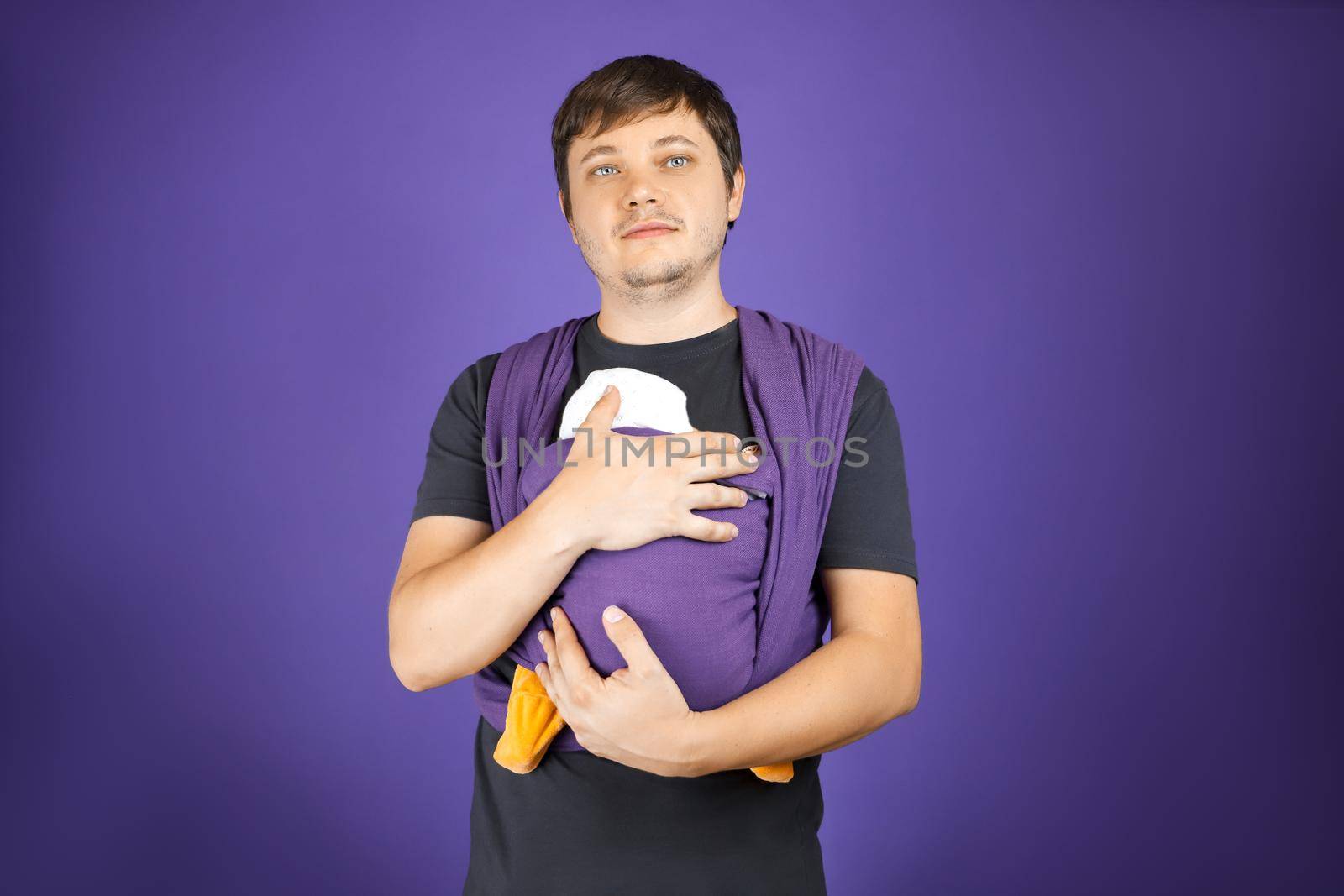 Young adorable father and baby in sling, front wrap carry. Happy fatherhood, free hand babywearing concept. by Rom4ek