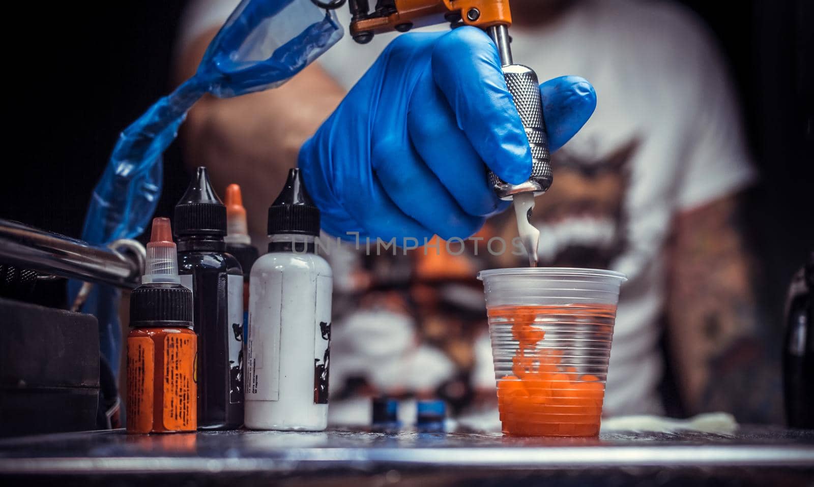 Hand of a master of the art of tattooing and a tattoo gun./Hand of a professional tattooer with a tattoo gun.