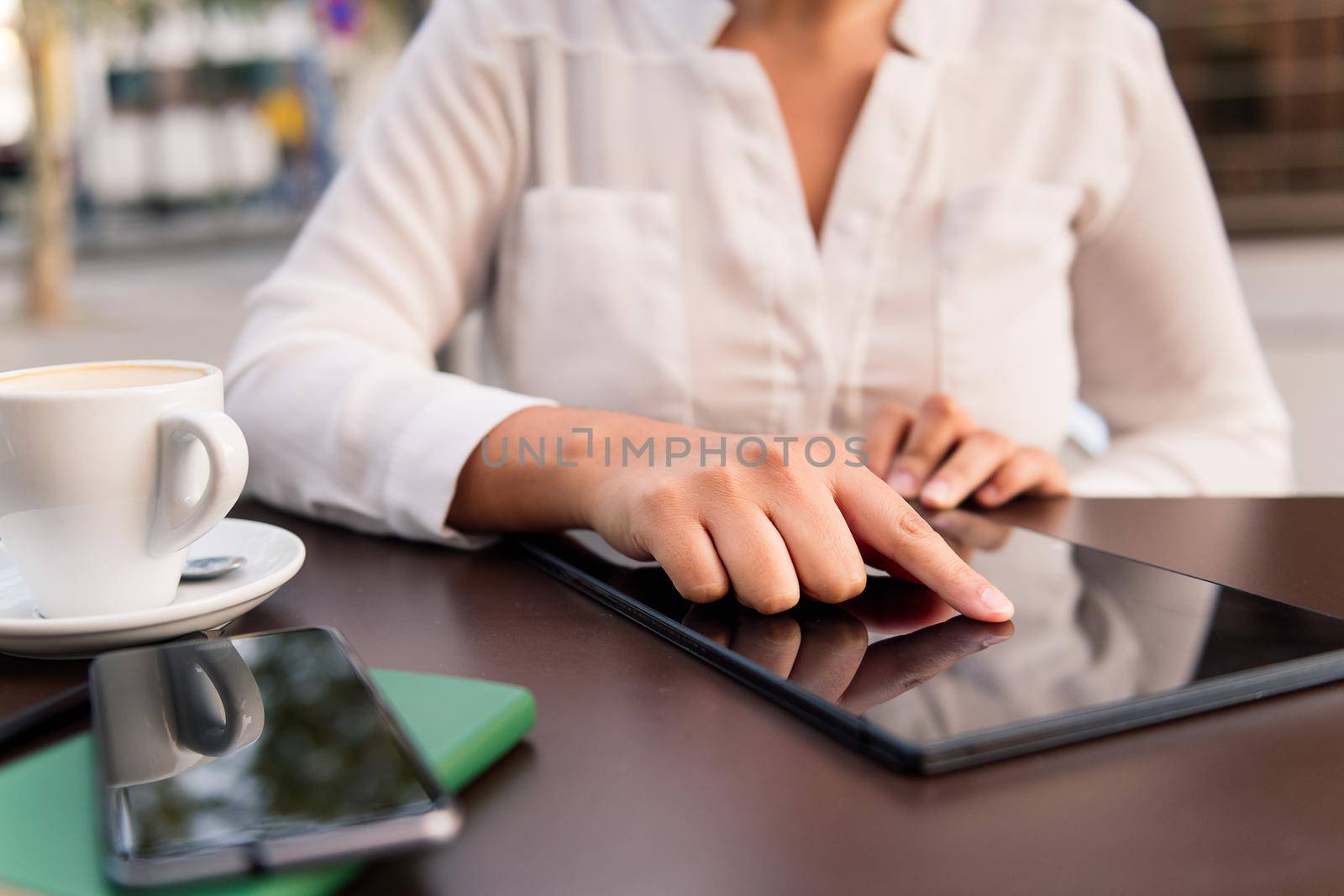 hand of a woman using a digital tablet on the terrace of a coffee shop, concept of digital entrepreneur and urban lifestyle