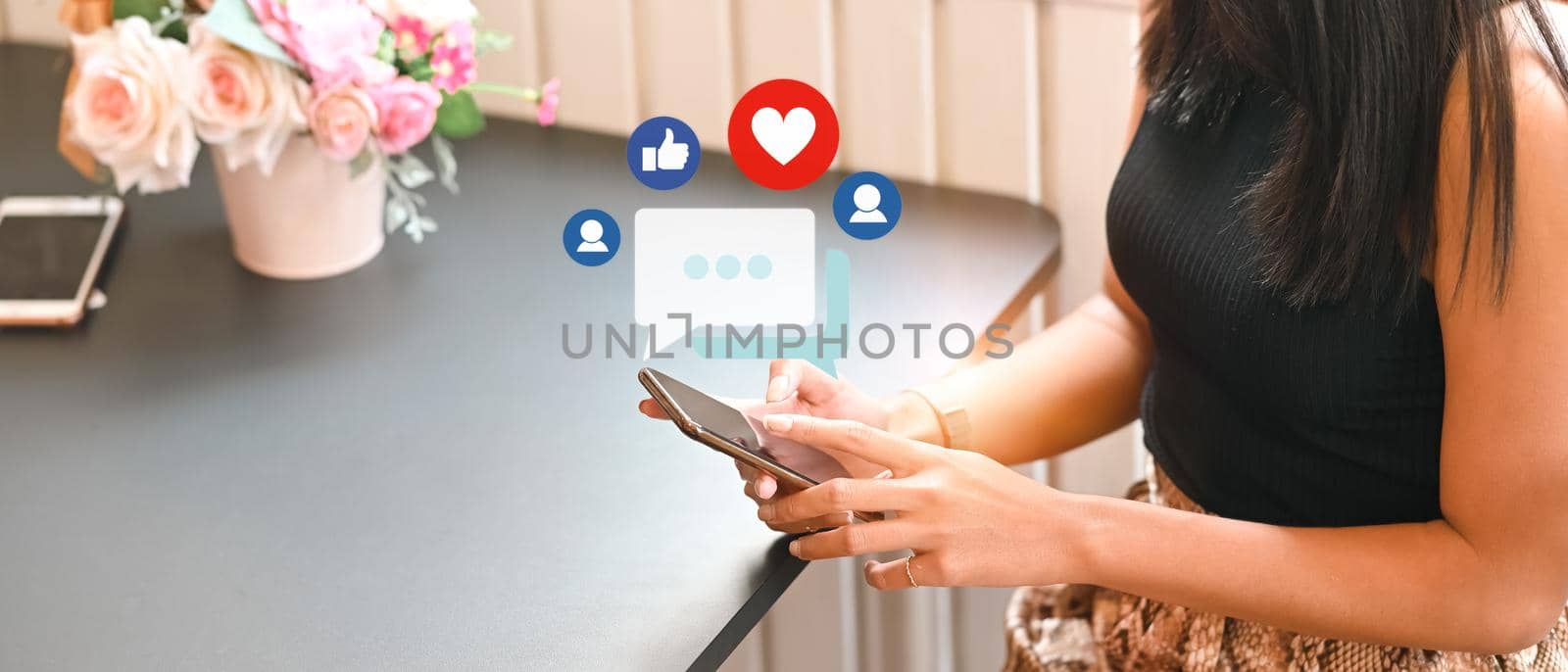 Woman using smart phone with notification icons of like, message and comment above smartphone screen. by prathanchorruangsak