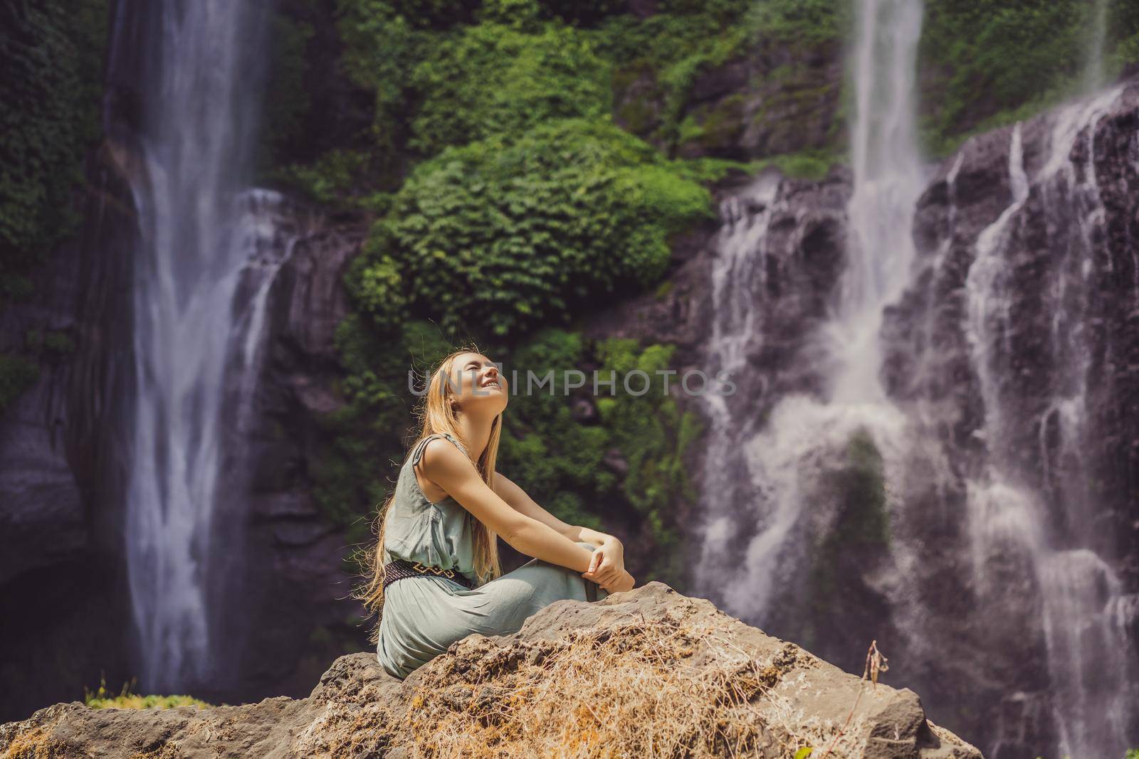 Woman in turquoise dress at the Sekumpul waterfalls in jungles on Bali island, Indonesia. Bali Travel Concept by galitskaya