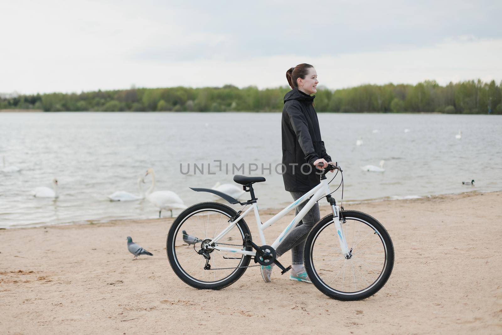 A young woman with a bicycle on the lake.