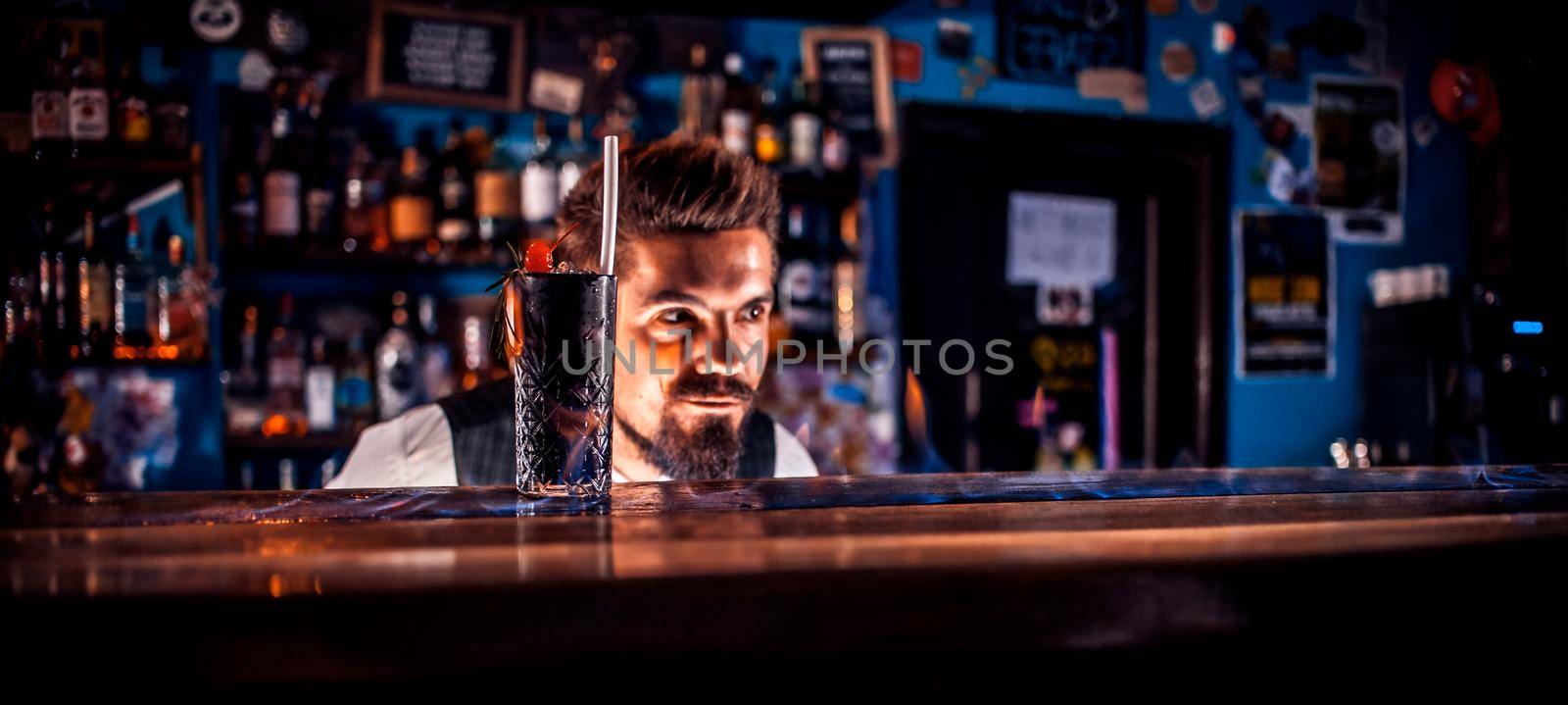 Professional bartender intensely finishes his creation on the bar