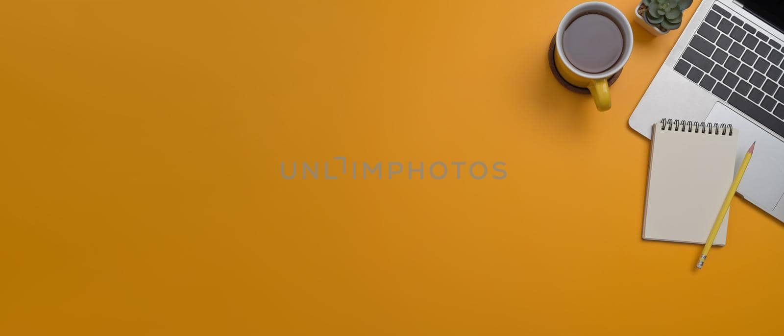 Laptop computer, coffee cup and notepad on yellow background with copy space for your information content. by prathanchorruangsak