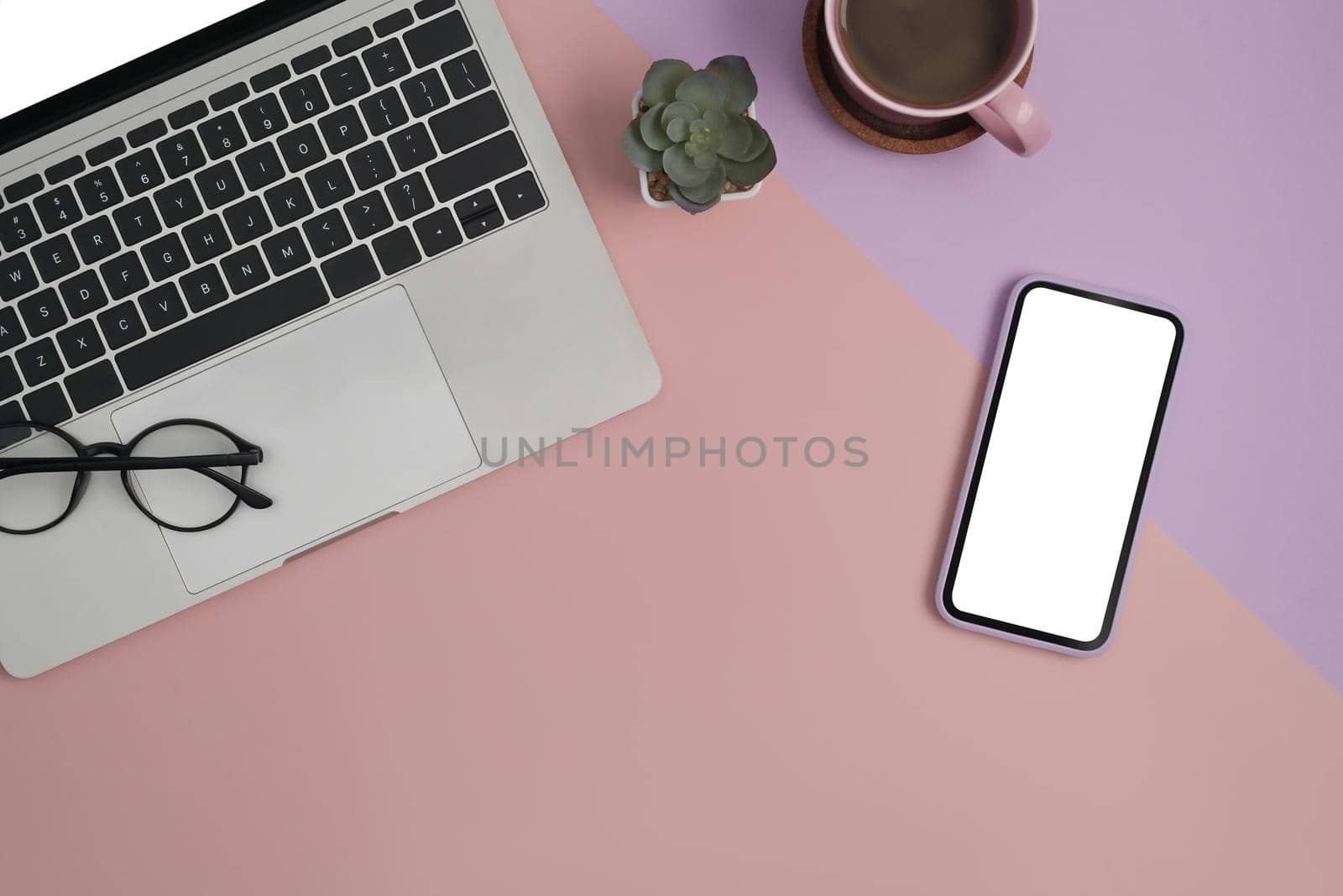 Computer laptop, smart phone, glasses, coffee cup and notebook on modern feminine workplace. Top view.