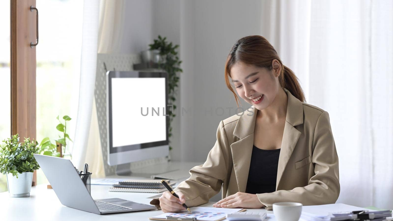 Pleased young business woman working at comfortable workplace.