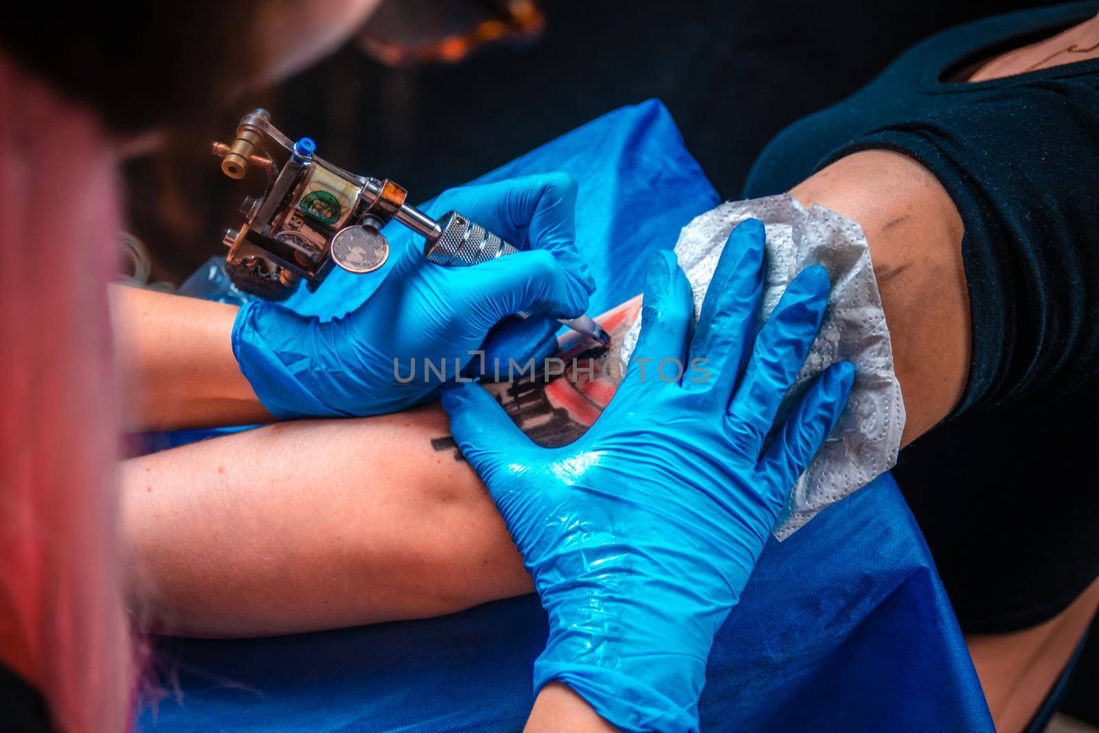 Master tattooist does tattoo on the skin of his client in tattoo parlour by Proff
