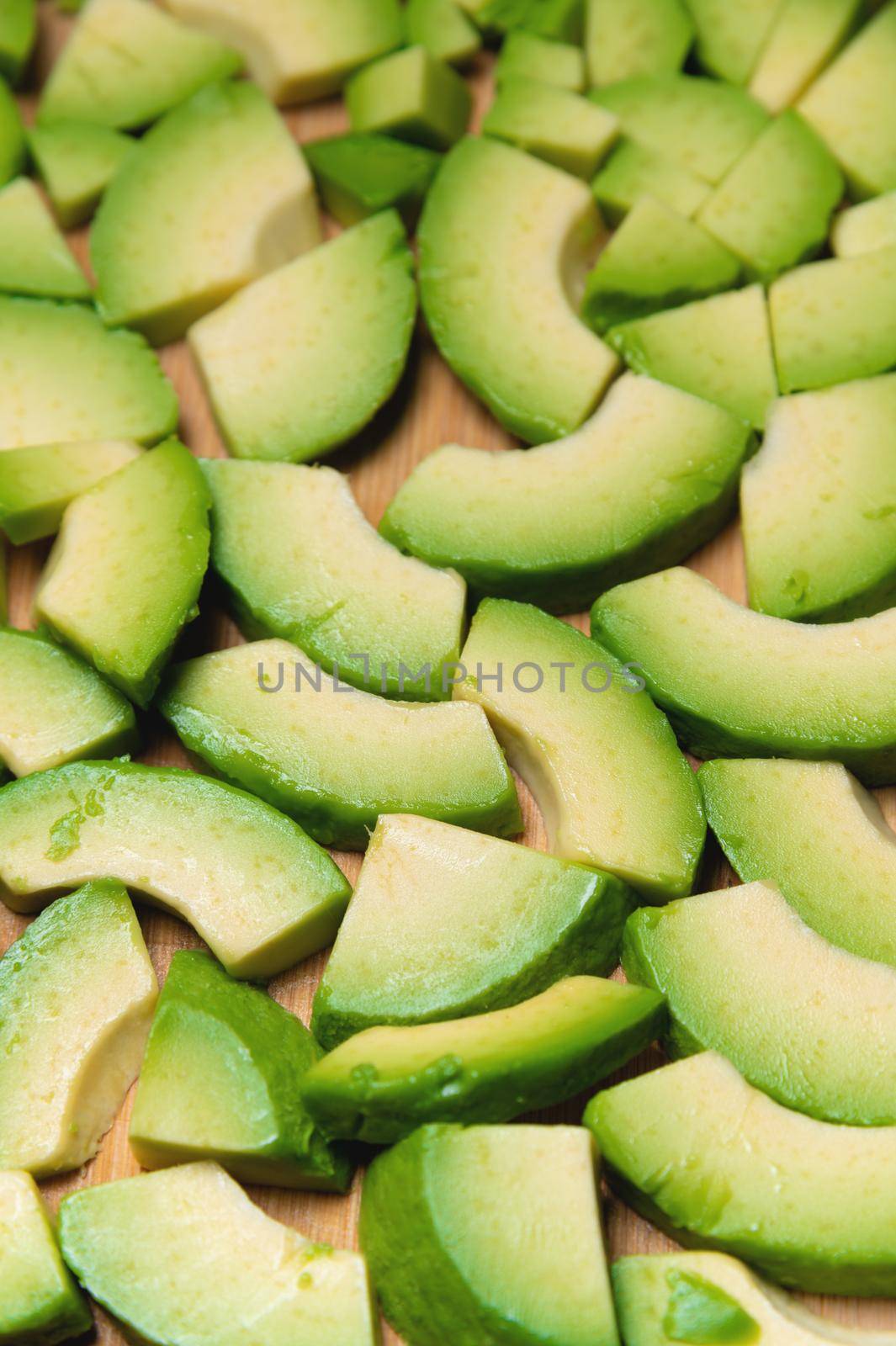 Avocado slices on a wooden board, on a gray table top view