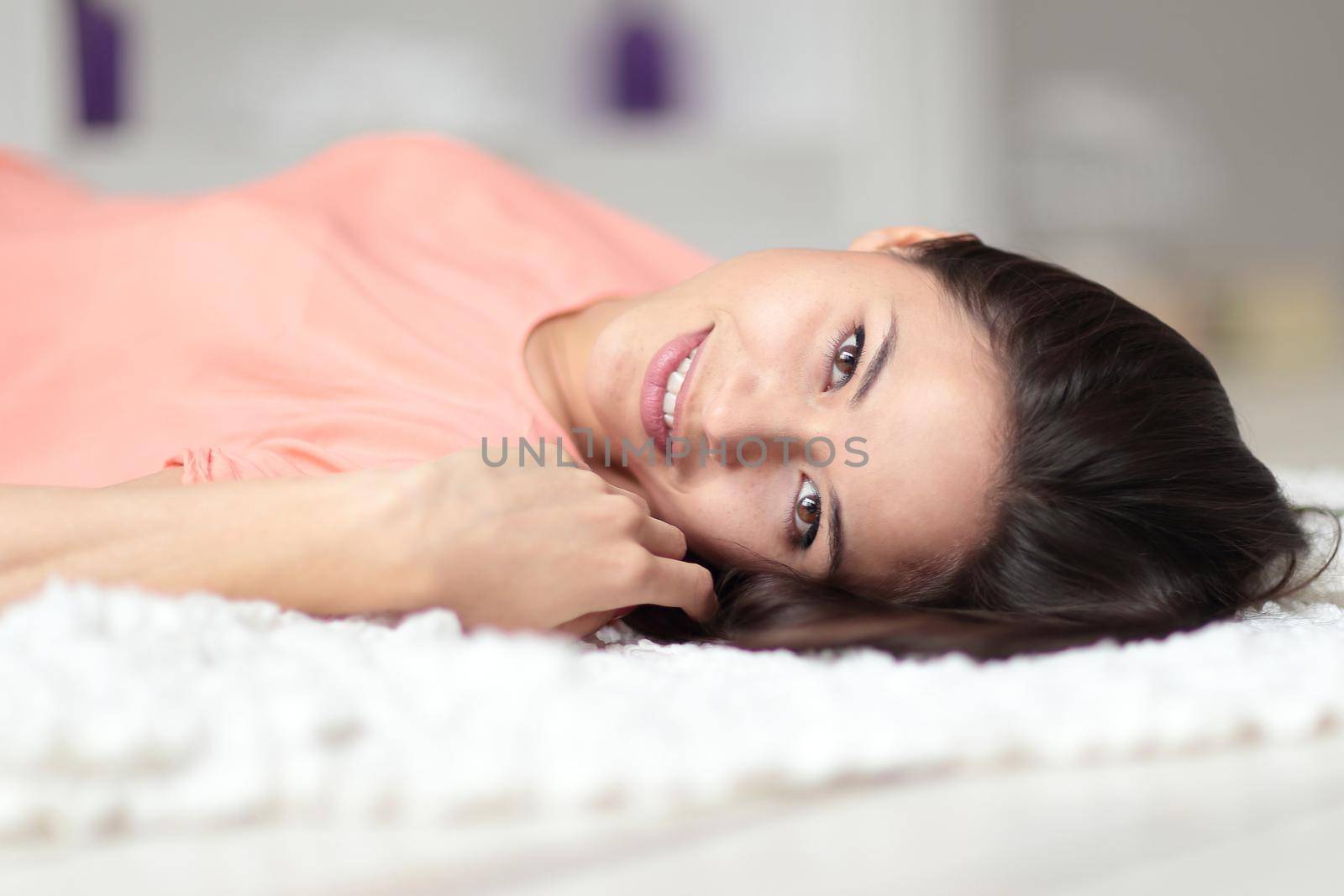 close up.smiling young woman lying on carpet in living room.