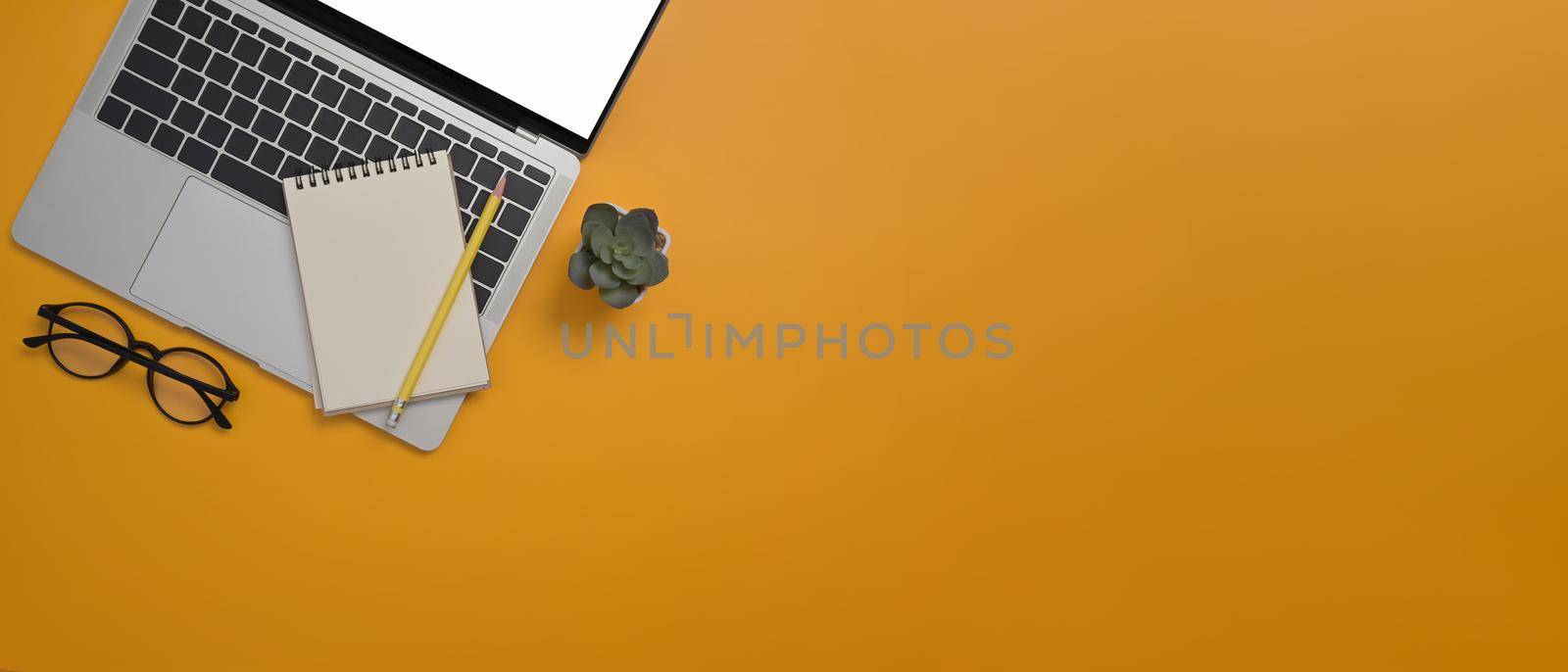 Mock up laptop computer, notepad, glasses and succulent plant on yellow background with copy space. by prathanchorruangsak