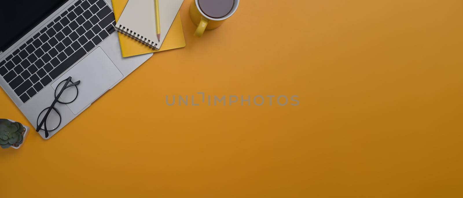 Computer laptop, notepad, glasses and coffee cup on yellow background with copy space. Flat lay, Top view. by prathanchorruangsak