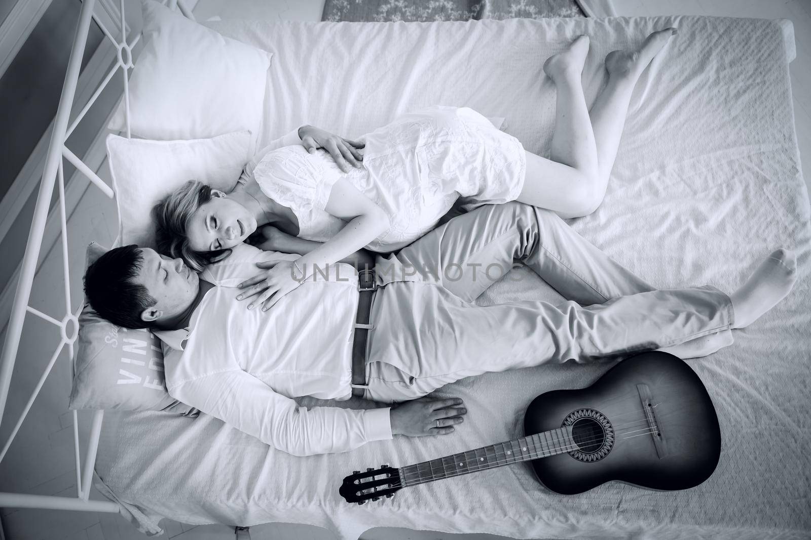 black and white photo in retro style.young married couple lying on the bed.the concept of family happiness