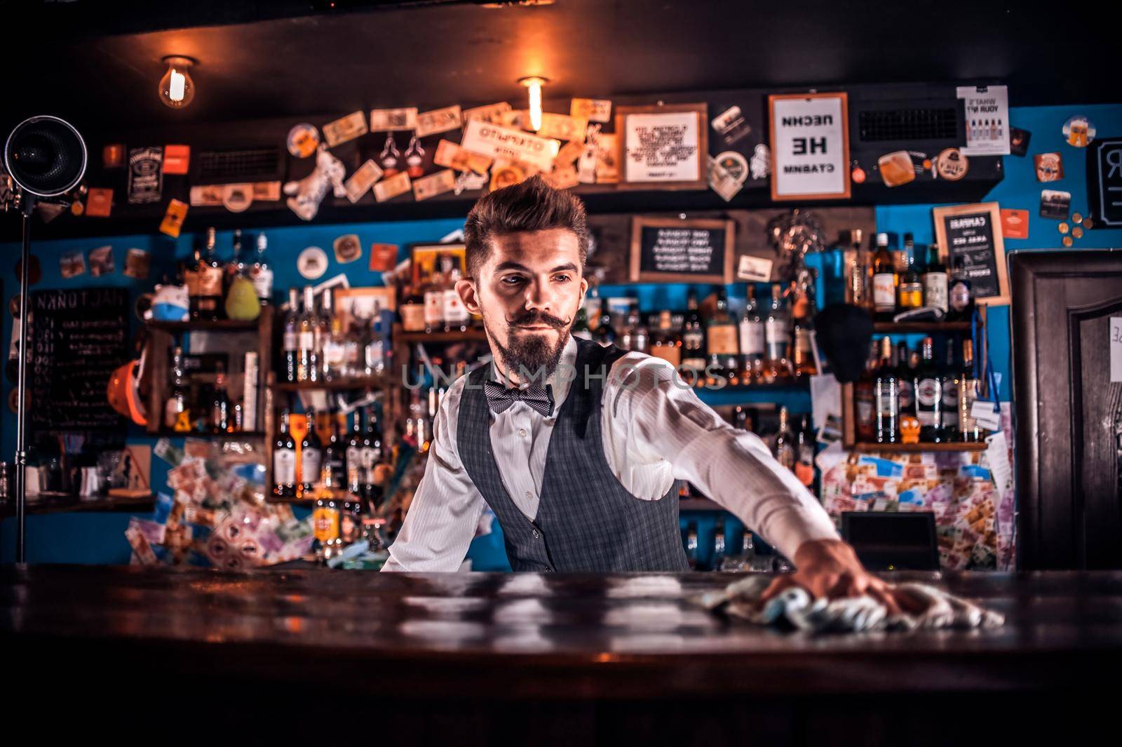 Young Female bartender intensely finishes his creation at the bar counter