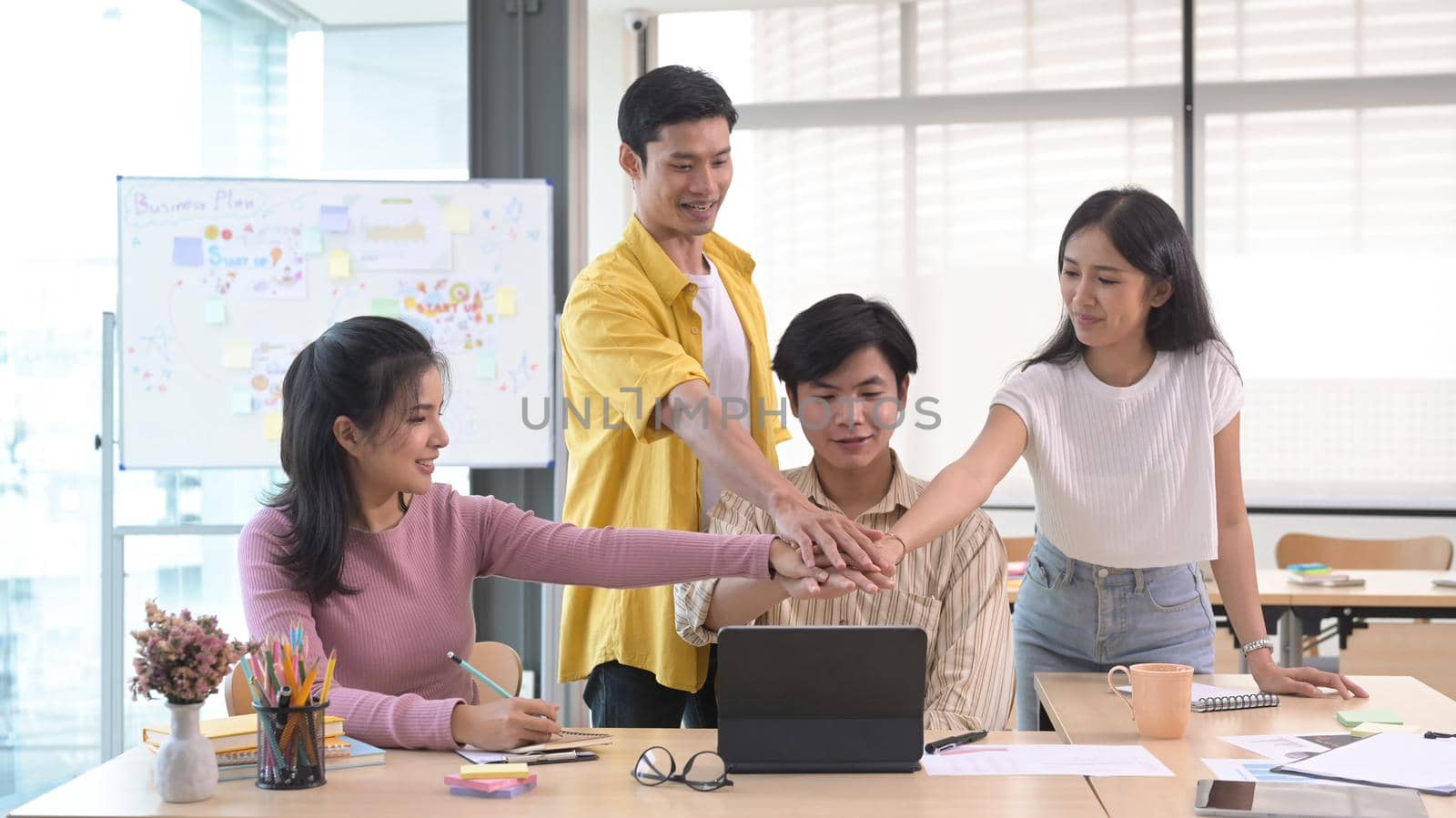 Startup business people are stacking hands over table, showing group unity, celebrating successful teamwork or achievement at meeting. by prathanchorruangsak