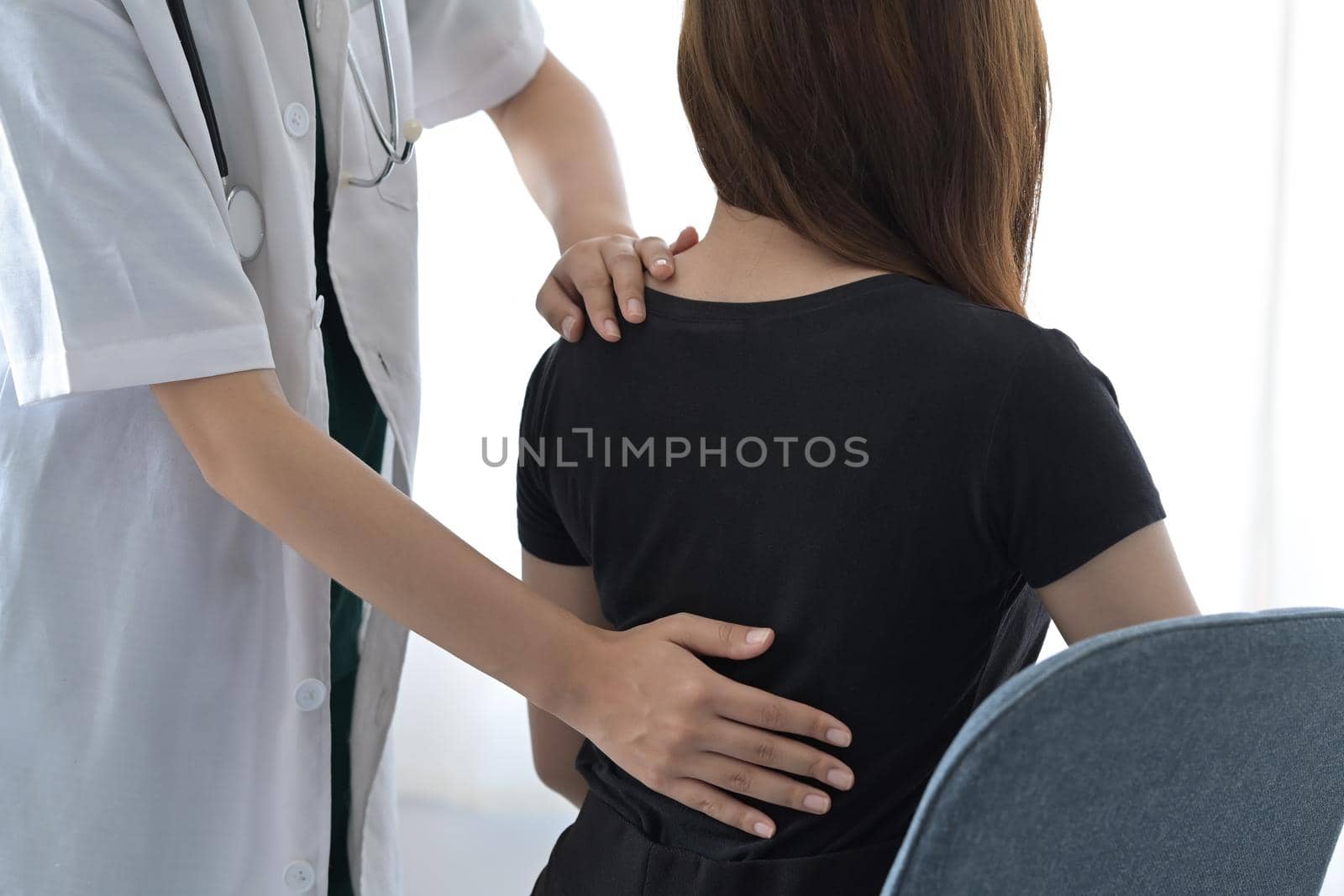 Cropped shot physiotherapist examining female patient injured back in medical clinic. by prathanchorruangsak