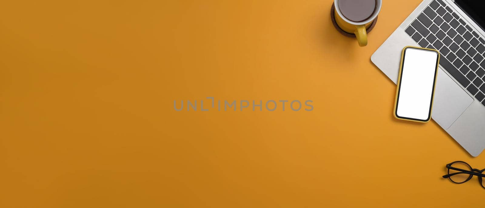 Top view laptop computer, smart phone, coffee cup and glasses on yellow background with copy space for your information content.