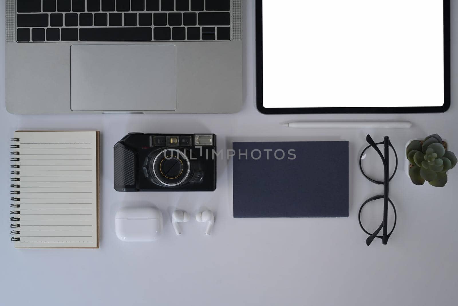 Flat lay designer workplace with digital tablet, camera, laptop, notebook and glasses.