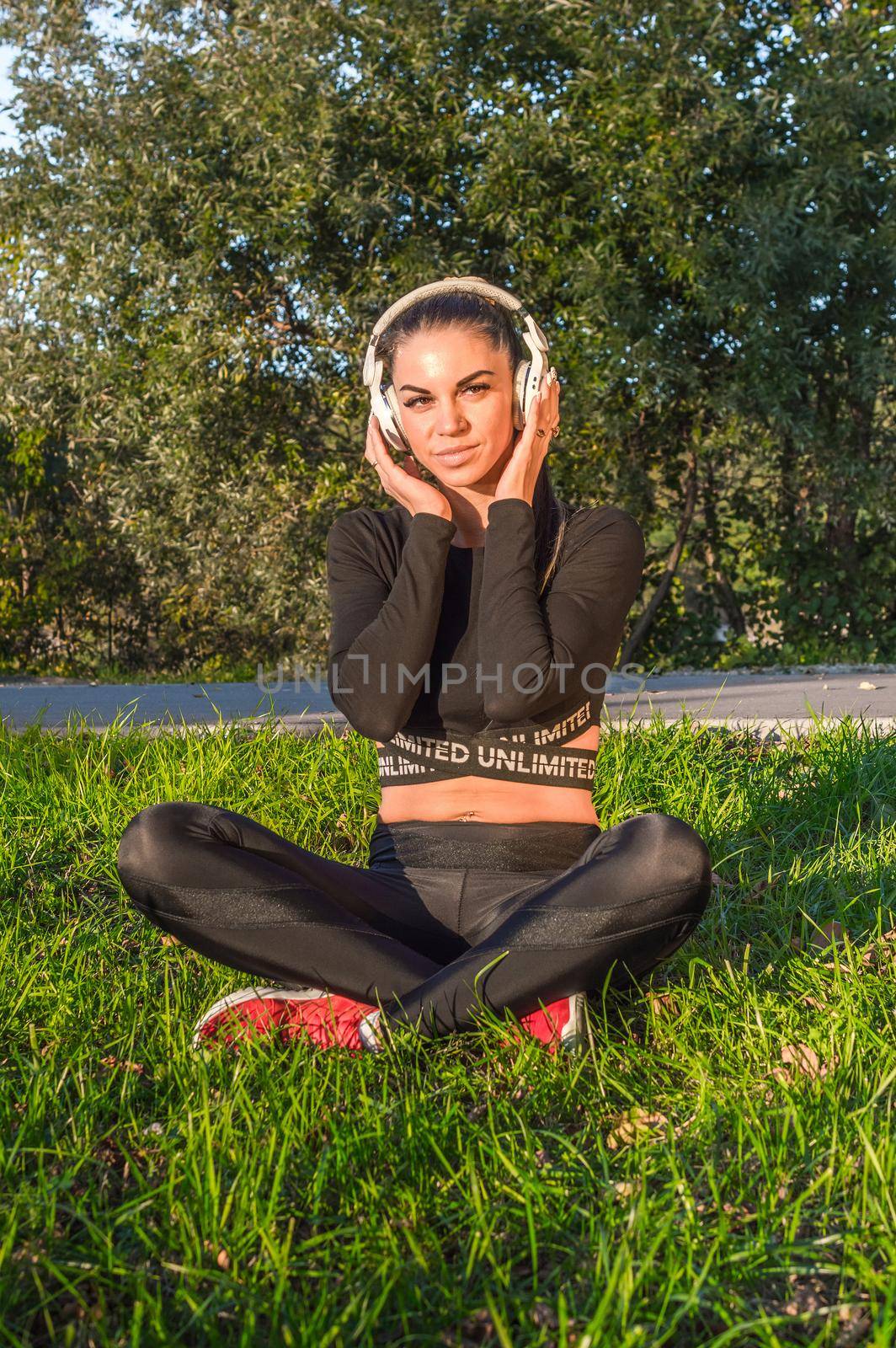 Nice sporty girl with headphones outdoors enjoying music./Athletic girl listens to music .