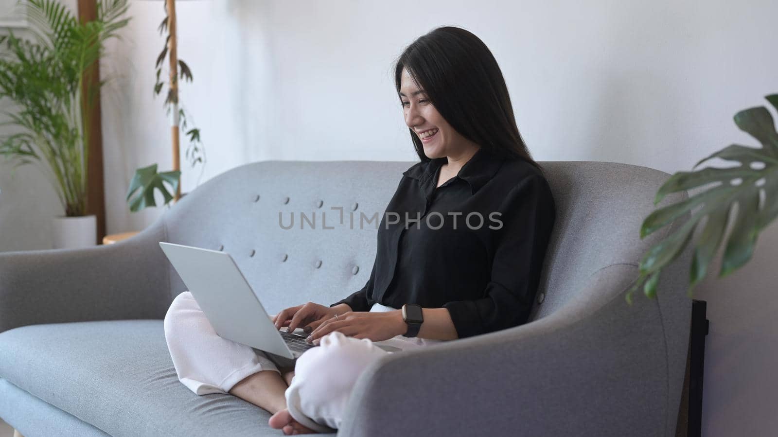 Smiling young woman freelancer working from home, surfing on internet on laptop computer.