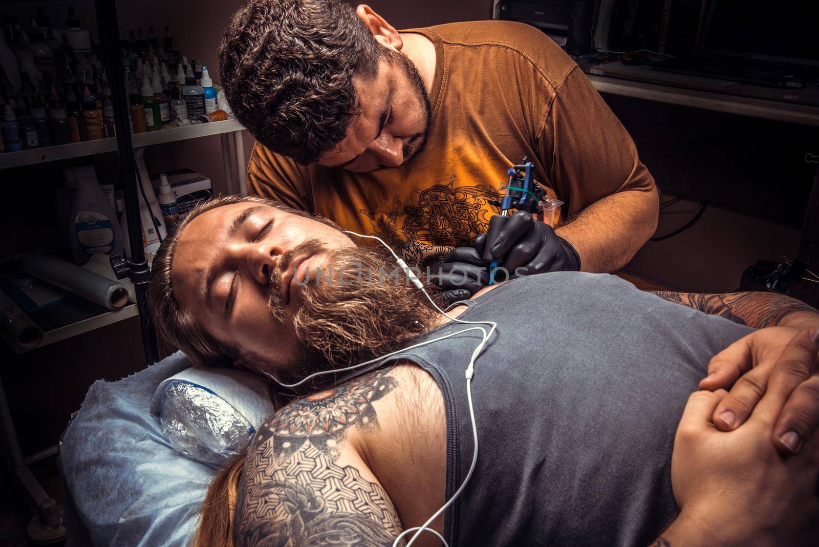 Tattoo artist doing tattoo in tatoo salon./Professional tattoo artist posing in tattoo studio.