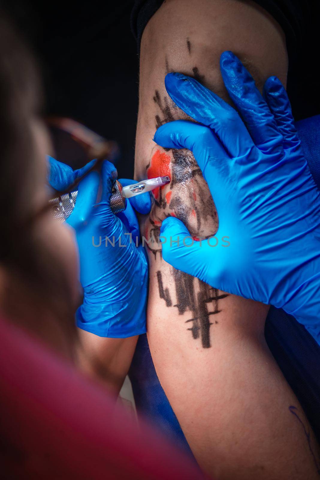 Master demonstrates the process of getting tattoo in tattoo studio./Tattooist at work in his salon.