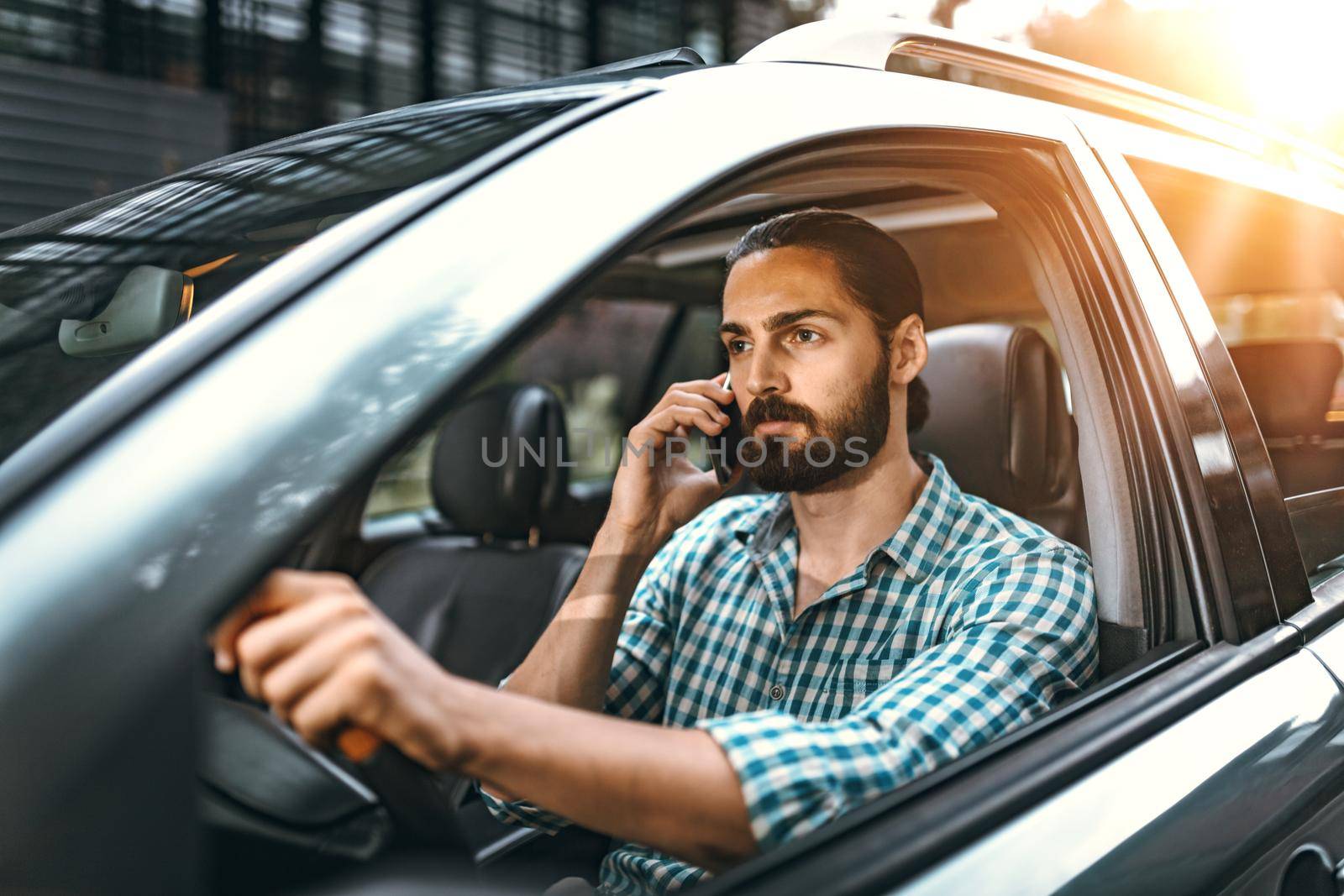 Man is holding smartphone in his hand and talking while driving a car.