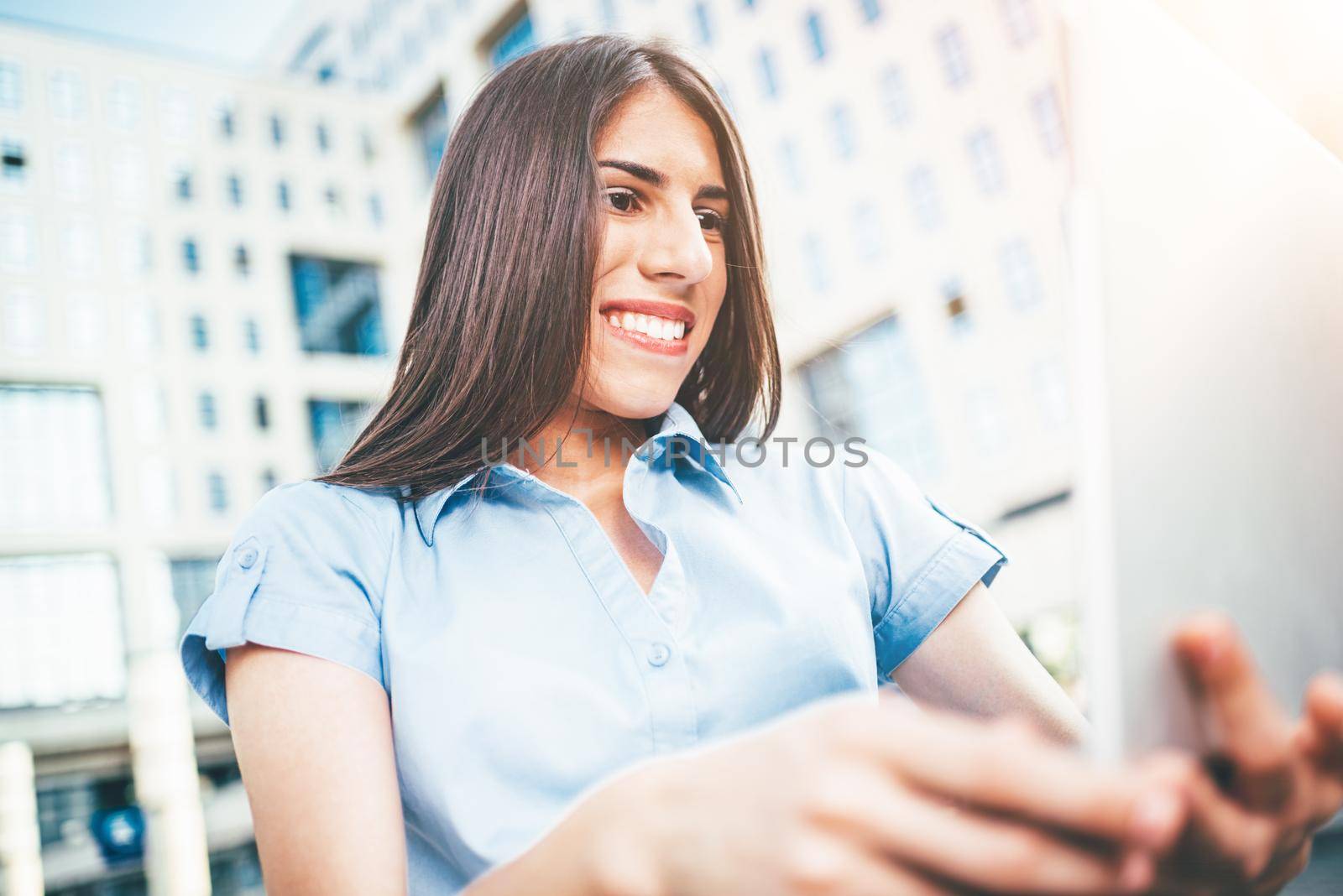 Emotional portrait of a happy and beautiful young businesswoman who working on laptop on the background of a business center.