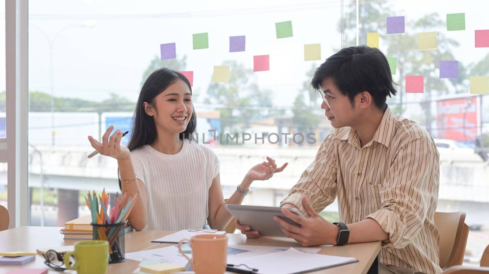 Confident young businesswoman explaining new online project to her colleague. by prathanchorruangsak