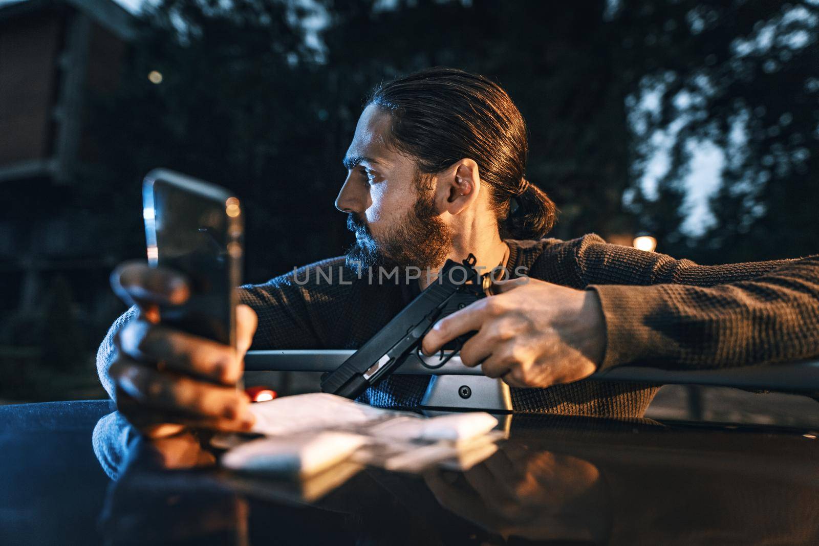 Dangerous criminal man with gun exchanging messages with his criminal boss to tell him  the order done and counting the money.