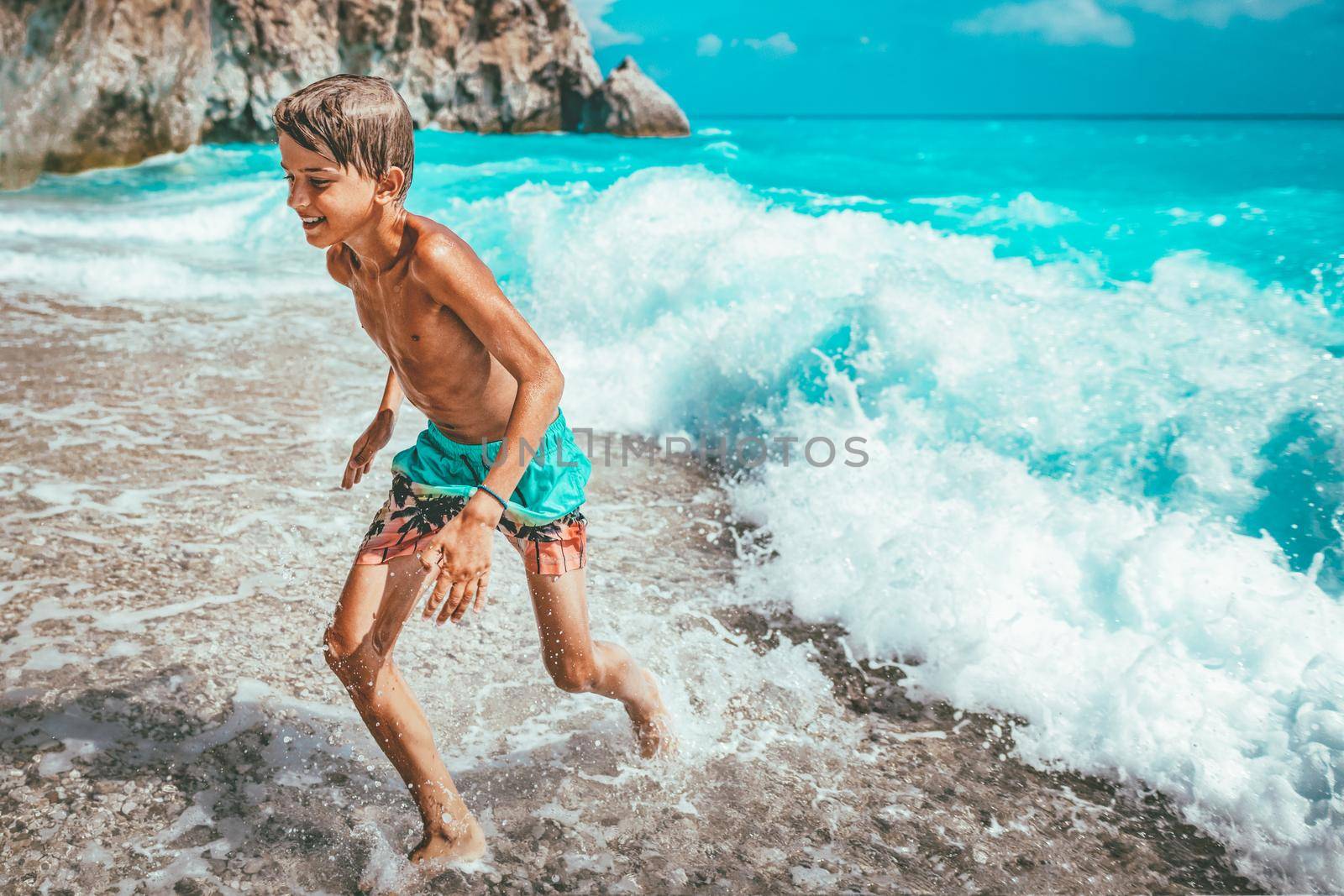 Cute boy enjoying on the beach running from the sea waves. 
