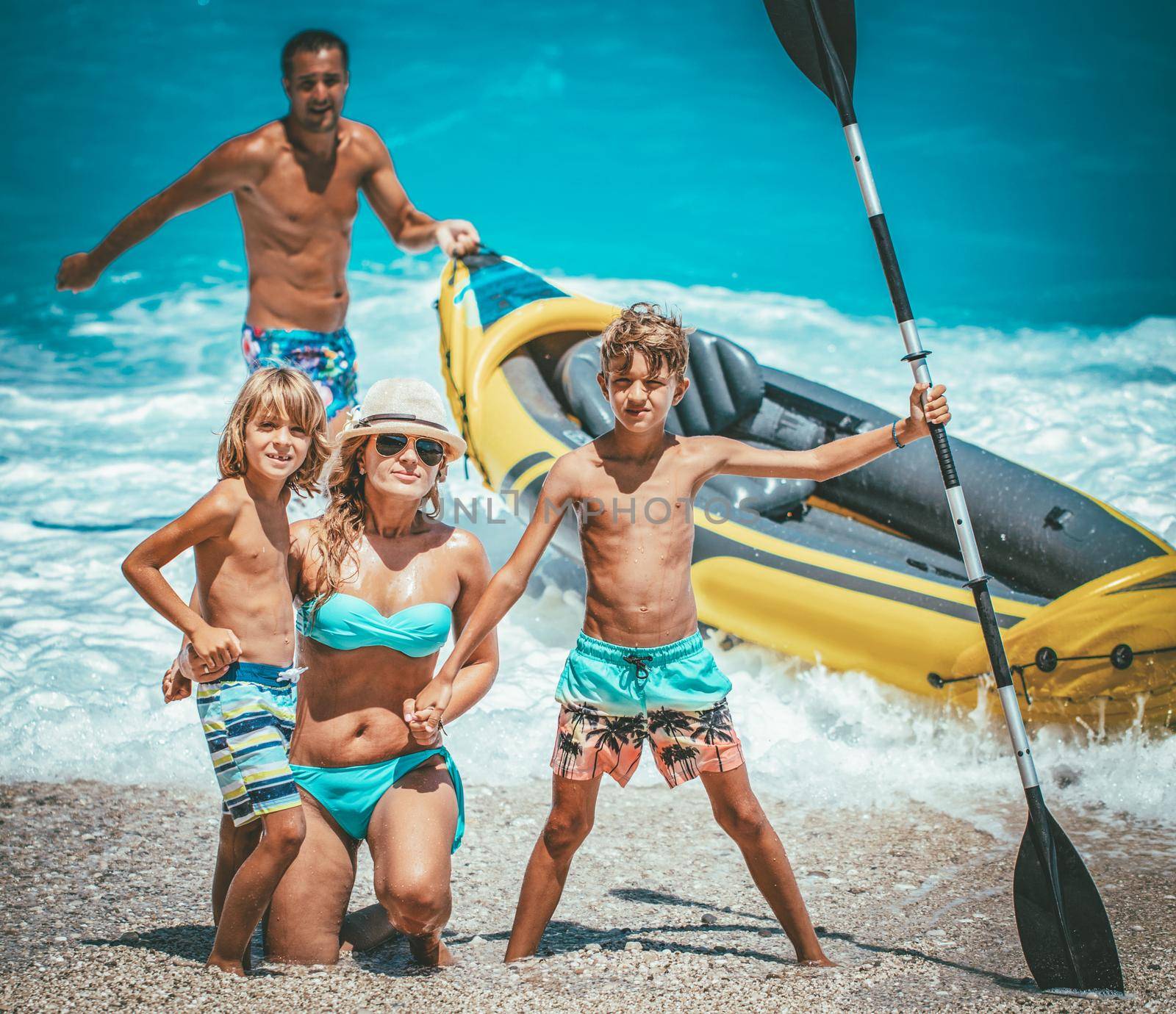 Happy family preparing rubber kayak for sailing at the beach. 