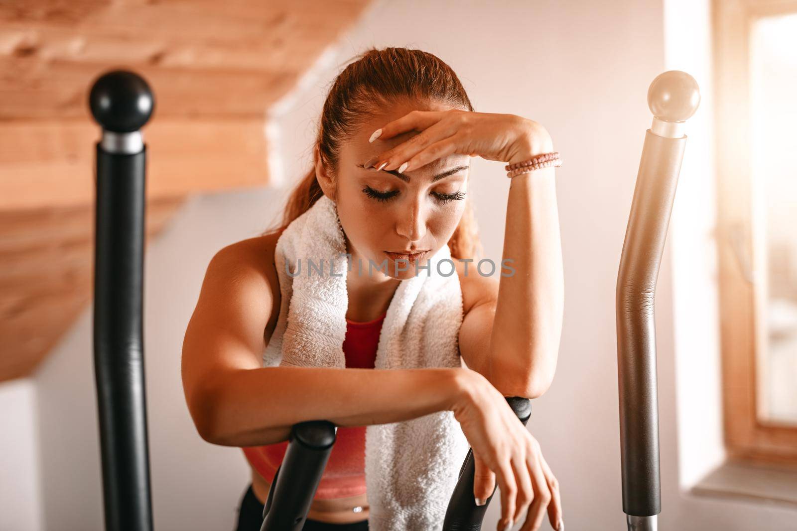 Attractive woman is exhausted and taking a break from hard exercising in living room at home.